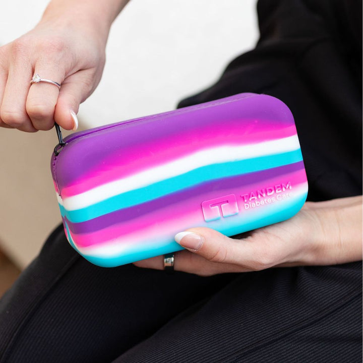 Person holding a colorful striped case with 'Tandem' branding.