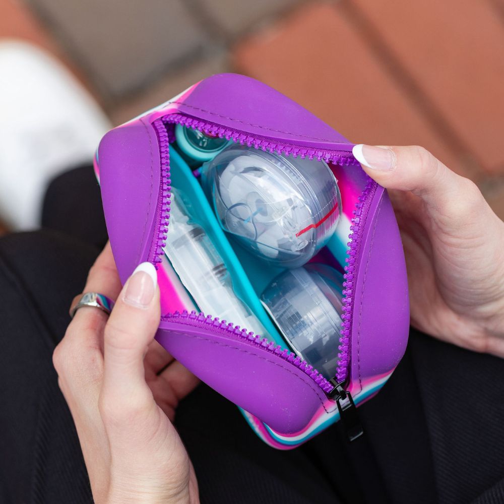 Purple, pink and blue travel case with Tandem Supplies held by hands against a blurred background