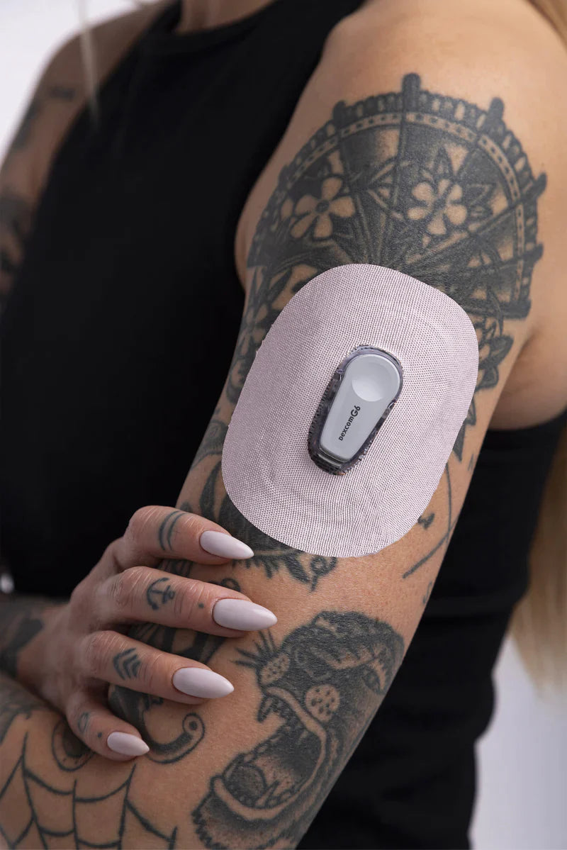 A person wearing a white Skin Grip adhesive around the Dexcom G6 sensor on their upper left arm.