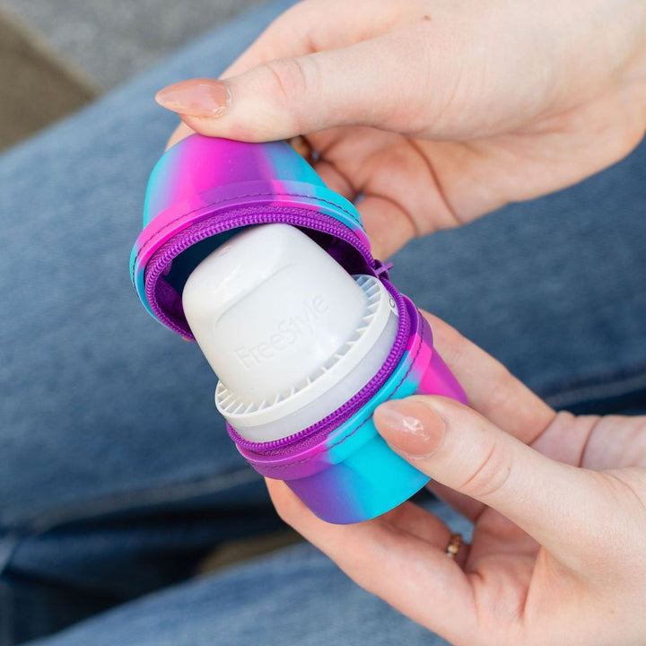Person holding a colorful Libre 3 Travel Protective case with a white Libre 3 inside.