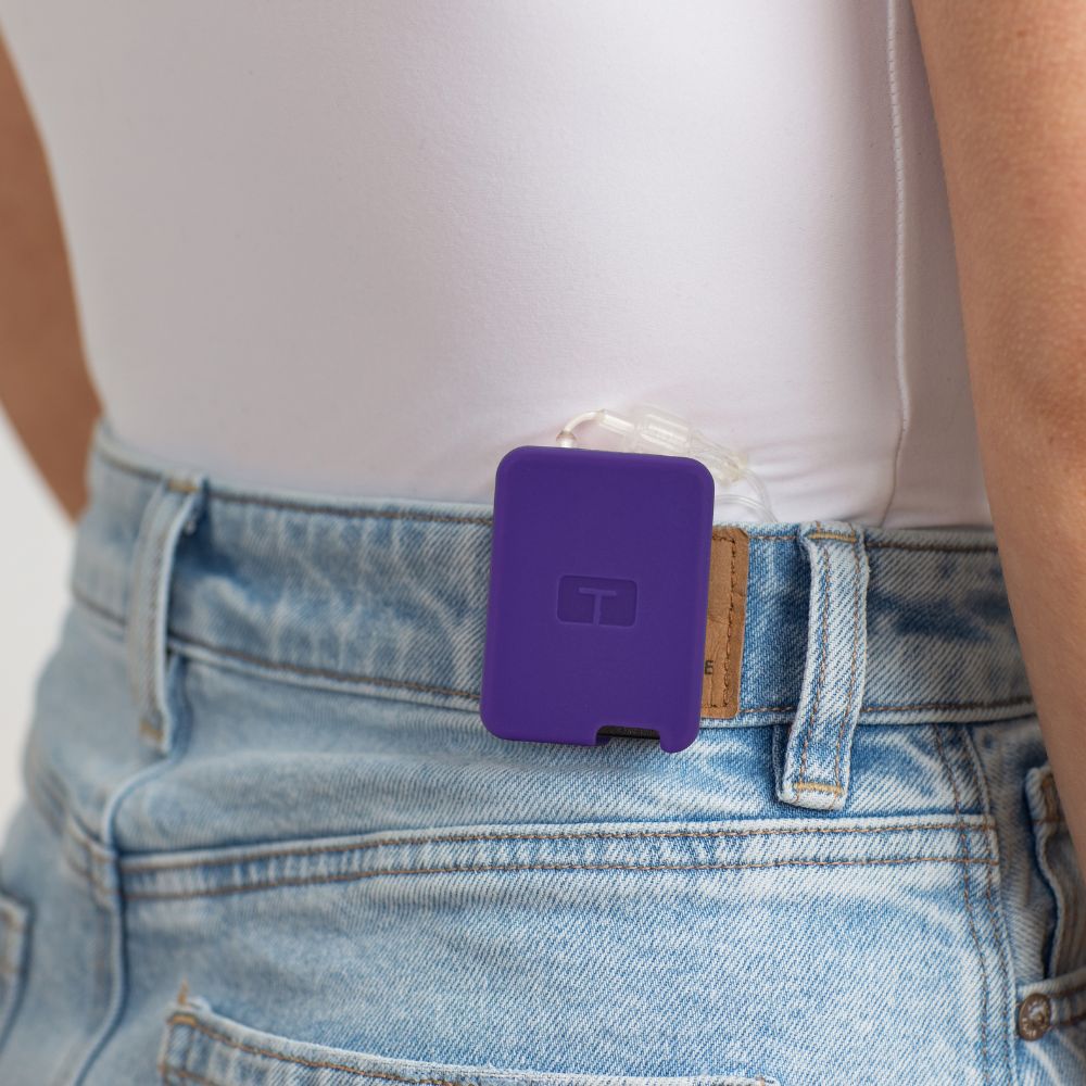 Girl wearing a white tee, with a purple Tandem Mobi EZ-To-Charge Clip attached to the back waistband of her jeans. 