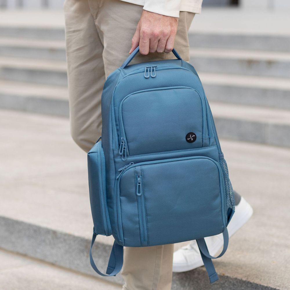 Person holding a Steel Blue backpack with a water bottle on steps