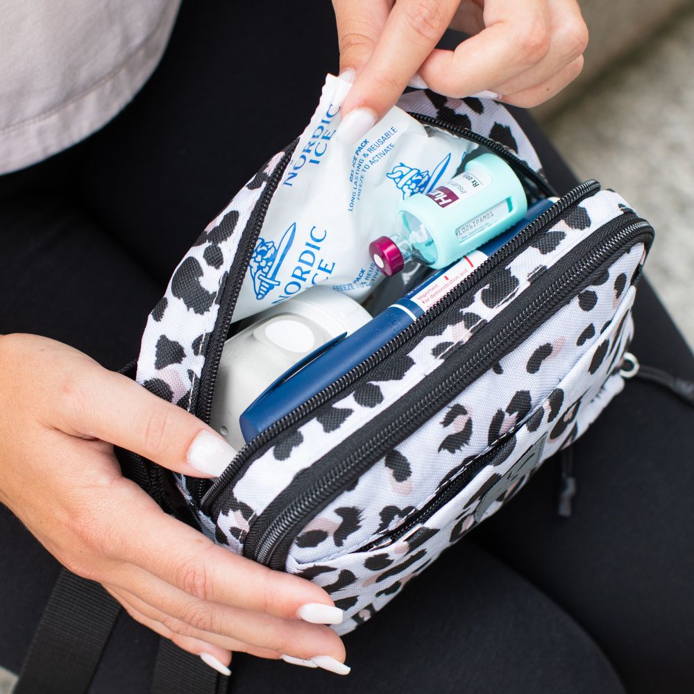 Women pulling ice pack out of the insulated packet of the snow leopard convertible diabetes case. 