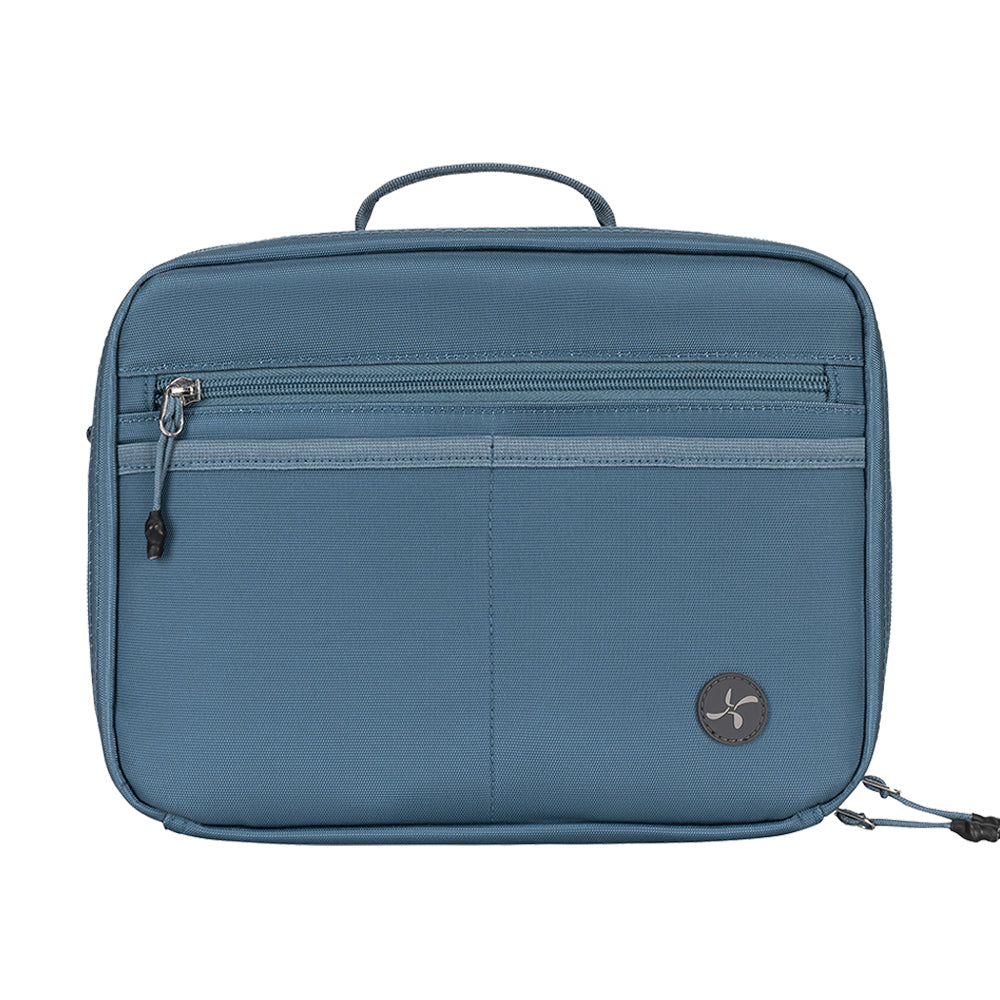 A steel blue soft-sided travel insulated diabetes supply bag with a top handle, a horizontal zippered pocket, and a circular black logo patch on the lower right, shown against a plain white background.