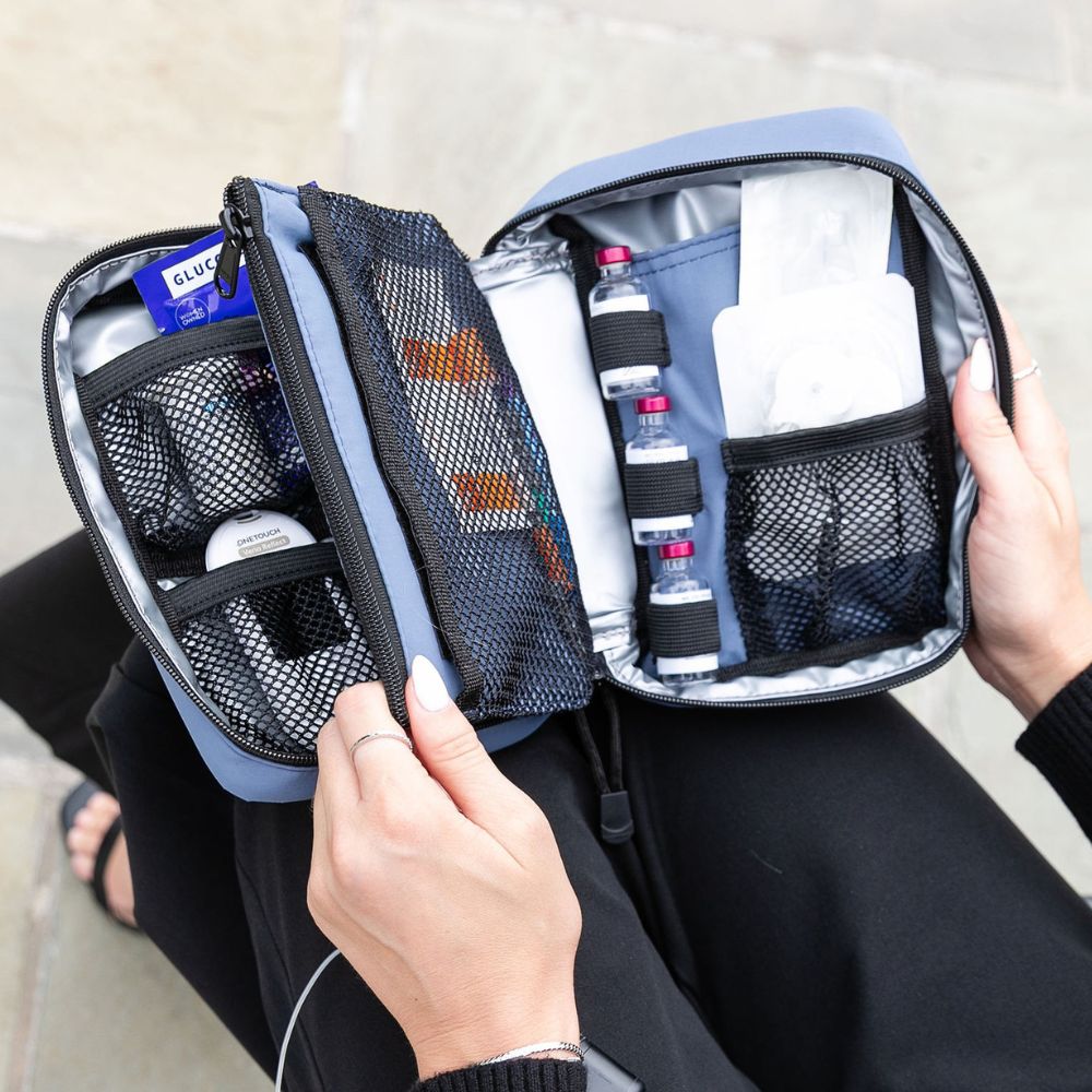 Woman holding open a Steel Blue Insulated Diabetes Organizer, displaying neatly arranged insulin and diabetes testing supplies.