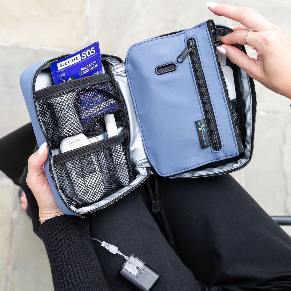 Woman holding open a Steel Blue Insulated Diabetes Organizer, displaying neatly arranged insulin and diabetes testing supplies.