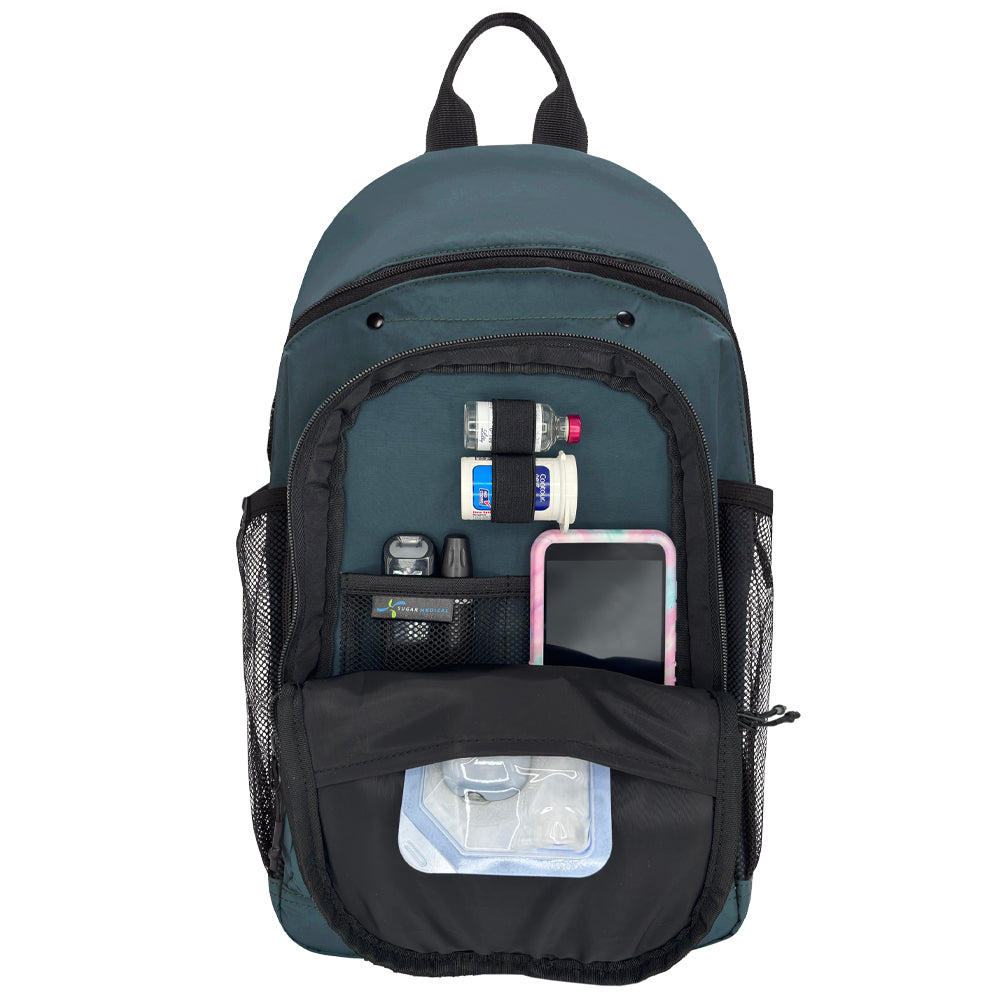 A dark teal backpack shown open against a white background, displaying its front organizer pocket filled with diabetes supplies.