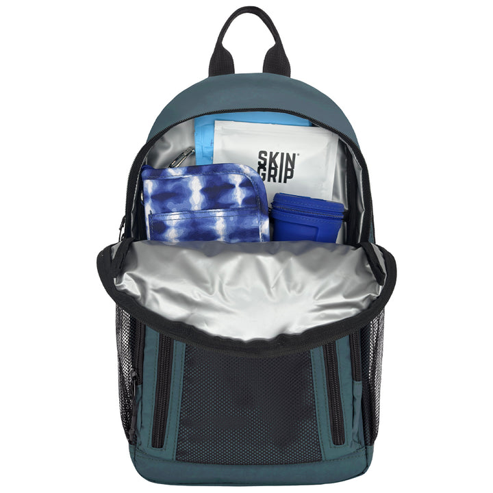 An open backpack shown from the front, revealing a silver-lined interior with folded blue and white items inside, including a white pouch with black text reading 'SKIN GRIP'. The backpack itself is dark teal with black mesh side pockets and black trim, photographed on a plain white background.