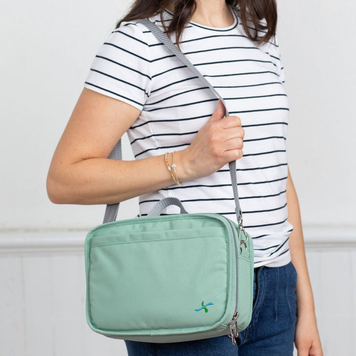 Women in stripe top wearing seafoam insulated diabetes travel bag on her shoulder, highlighting its grey shoulder strap. 