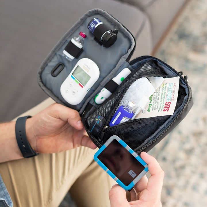 Man holding tandem supply case open with inside set up containing diabetic supplies while reading his tandem pump