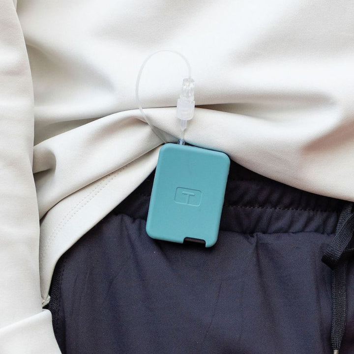 Man wearing a white tee, with a teal mist Tandem Mobi EZ-To-Charge Clip attached to the front waistband of his pants.