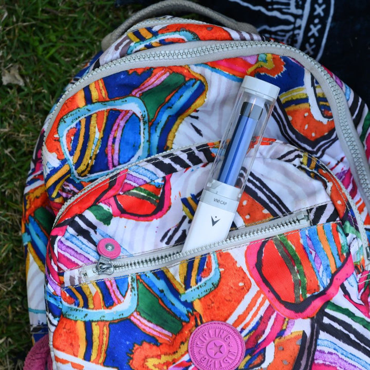 VIVI Cap coming out pf the front pocket of a backpack. 