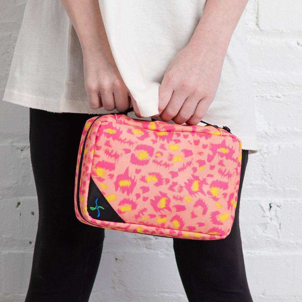 Girl with black pants holding the Wild Pink Insulated Diabetes Organizer by the handle in one hand. 