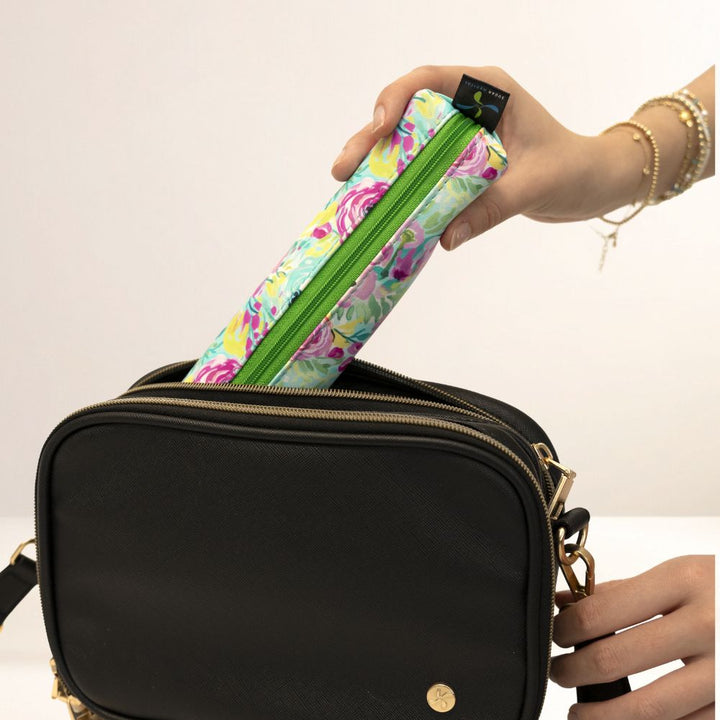 Person holding a floral-patterned MedMate with a green zipper over a black handbag.