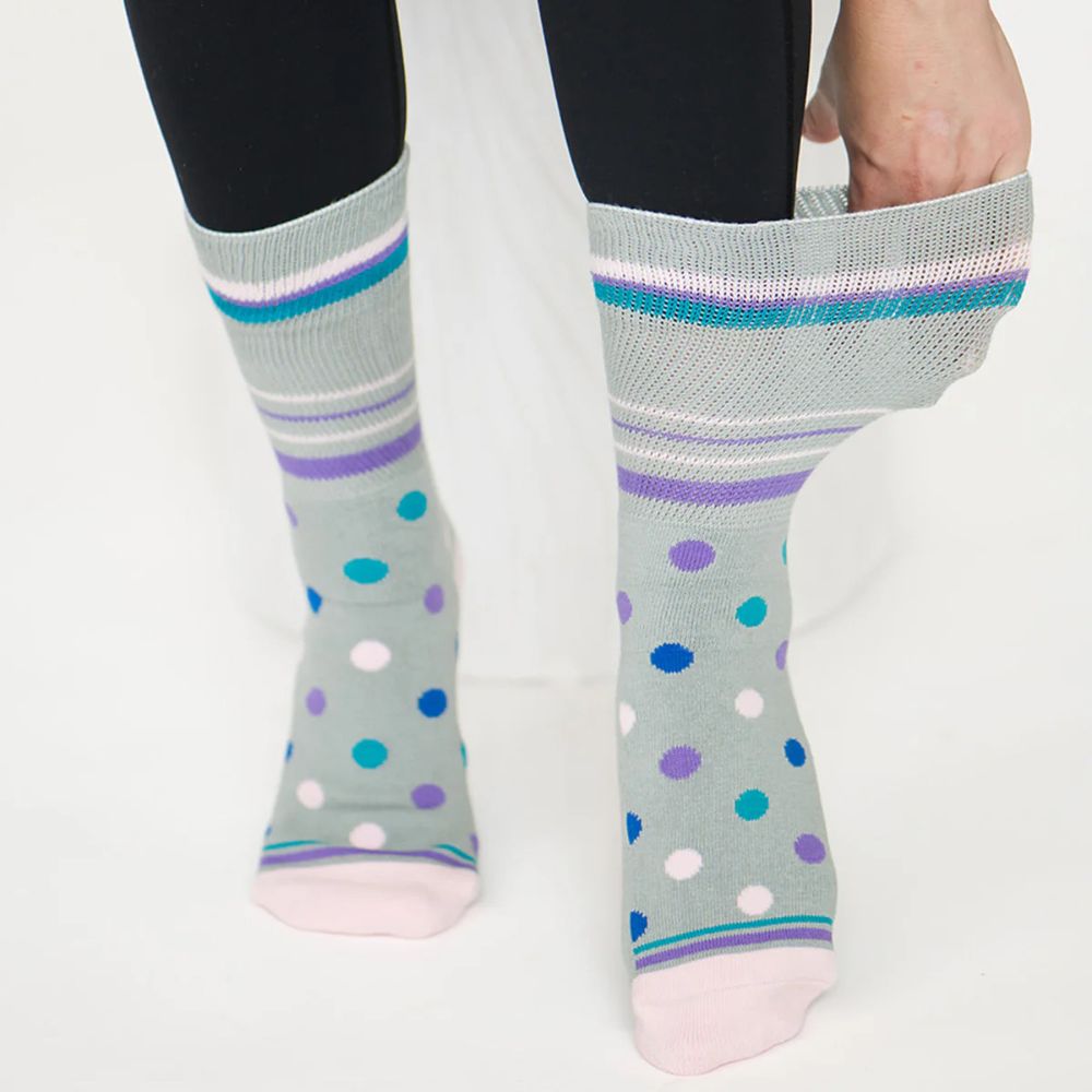 Two legs wearing Dr. Segal grey polka dot socks. 