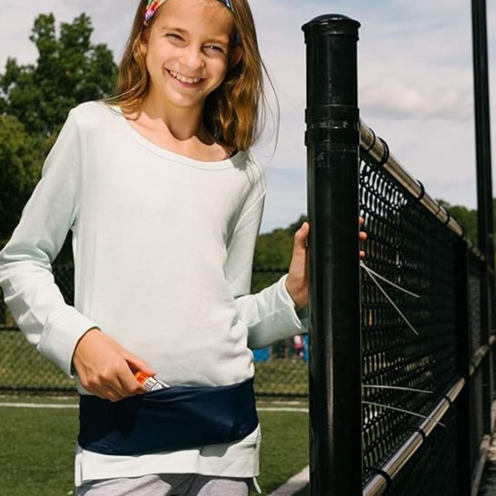 Girl wearing a kids' black Bandi Wear Pocket Belt, pulling an insulin pen out of the pocket, highlighting its practical design for carrying essential medical supplies.