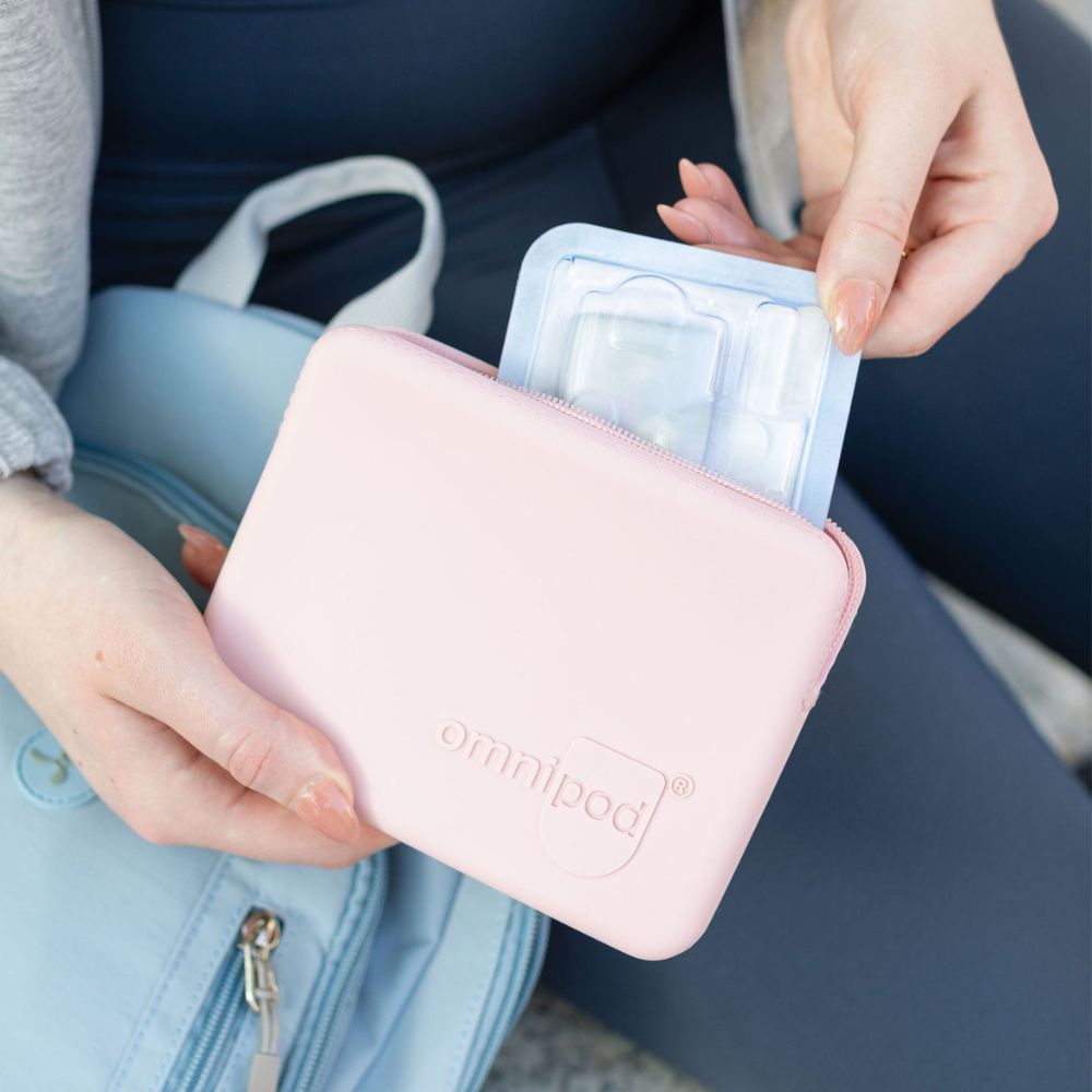 Person holding a light pink Omnipod travel case with 'omnipod' branding, containing medical supplies.