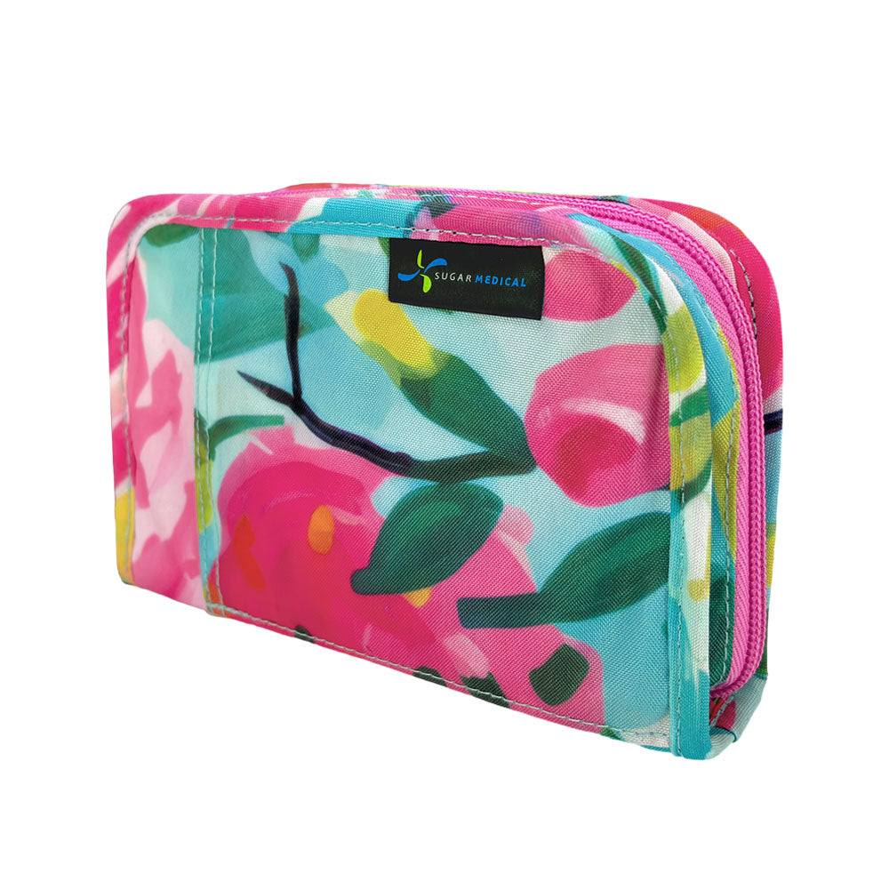 Colorful floral-patterned diabetes supply case with a visible Sugar Medical label and pink zipper on a white background