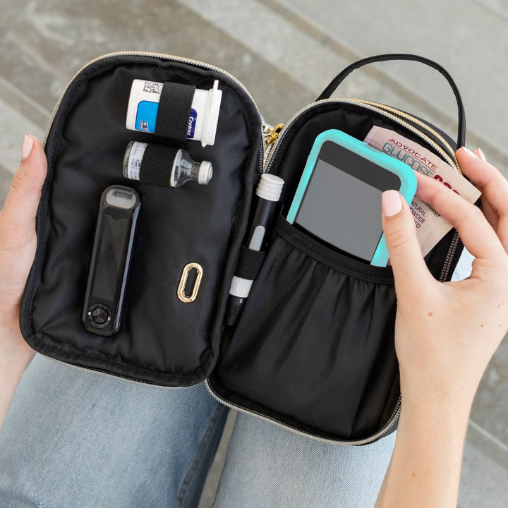 Woman has nylon diabetes purse in her lap and is pulling out her supplies to test her blood. 
