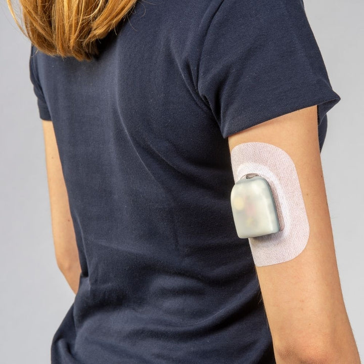 A woman in a black short-sleeved shirt wearing the pod and Podpal on the back of her right arm.